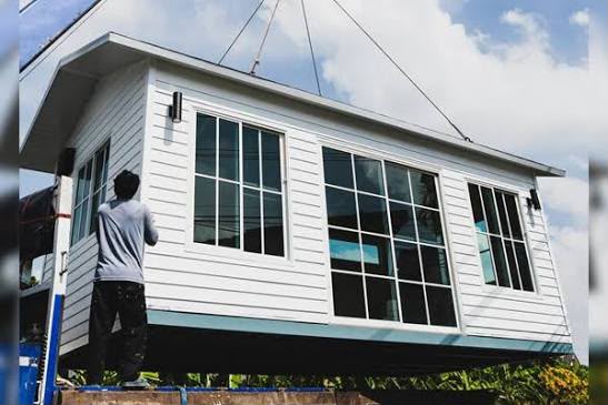 Casa prefabricada elevada por una grúa durante su instalación
